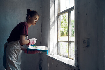 woman painter paints window with brush renovation interior decoration