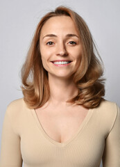 Portrait of young woman in beige shirt with long sleeves and volumetric blonde curly hair, with open friendly smile looking at camera