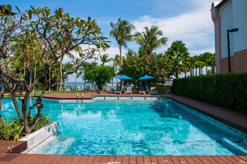 Fototapeta na wymiar Swimming pool near ocean with blue sky in summer