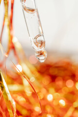 Pipette with gel on the background of tinsel.