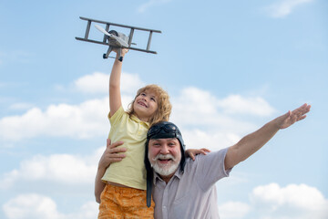 Child boy and grandfather playing with toy airplane against summer sky background. Weekend with granddad.