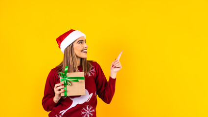 Portrait of Latin woman holding Christmas gift box on a yellow background in Mexico latin america