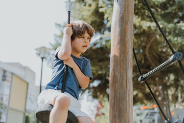 little brunette boy in white shorts and a blue T-shirt is hanging on a street simulator. child is engaged in outdoor sports. space for text. High quality photo