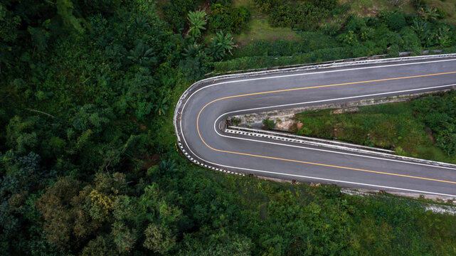 Aerial view asphalt road in mountain pass with green forest, Countryside road passing through the green forrest and mountain. © Kalyakan