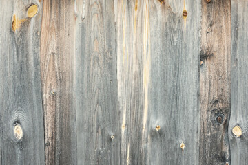 Fragment of the wall of an old wooden barn. The surface of the boards is gray from the influence of nature and time. Background. Texture.