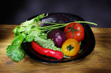 Vegetables and green parsley on a black plate.