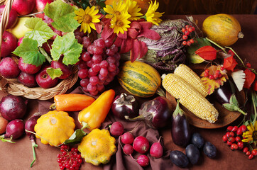  A variety of vegetables, grapes and flowers on a wooden table.