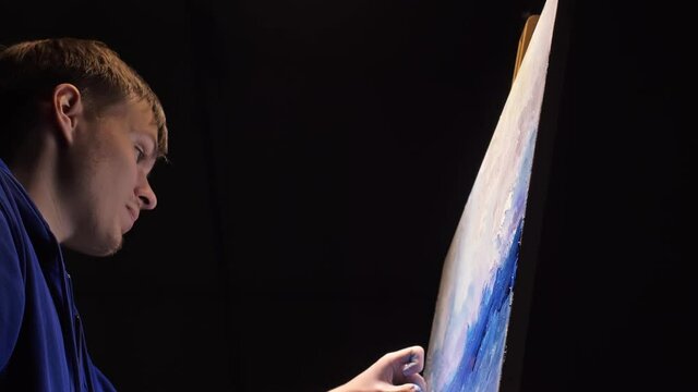 Artist copyist paint seascape with ship in ocean. Craftsman decorator draw as boat sail on blue sea with acrylic oil color. Draw finger, brush, knife palette. Indoor. Dark magic cinematic look.