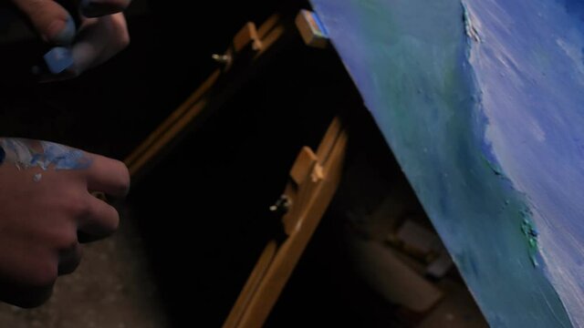 Artist copyist paint seascape with ship in ocean. Craftsman decorator draw as boat sail on blue sea with acrylic oil color. Draw finger, brush, knife palette. Canvas, easel in studio, indoor.