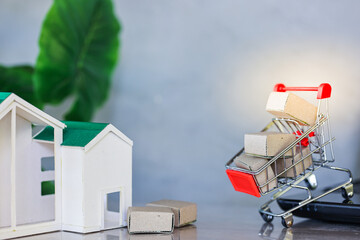 Shopping online and delivery concepts.
Miniature product package boxes in shopping cart and house models with laptop computer on wooden table.