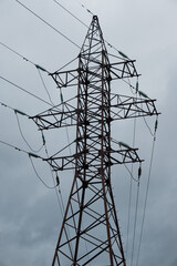 Openwork metal pylon of a power line against a background of a grey autumn sky