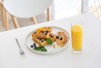 Delicious Belgian waffles with berries and fruits and a glass of juice.