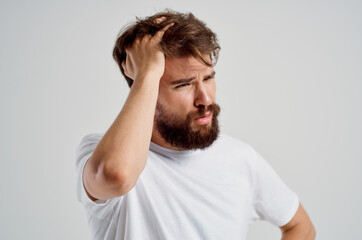 bearded man in a white t-shirt headache migraine problems light background