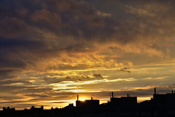 The city in the rays of the rising morning sun, against the backdrop of golden clouds. 