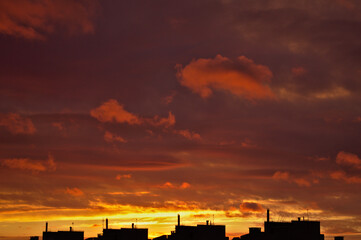 The scarlet and golden sunrise over the rooftops of the city creates a very beautiful composition. 