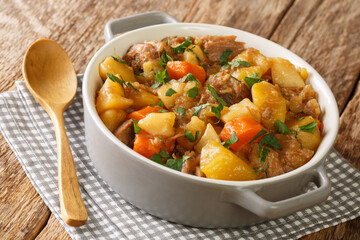 Delicious stew consists of potatoes, meat, onions and carrots close-up in a bowl on the table....