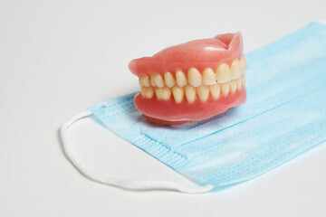 Dental dentures and medical mask on white background