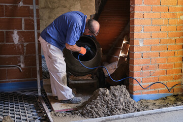 Construction worker cleaning the concrete the mixer with a water hose.
