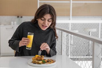 A woman is having breakfast with Belgian waffles and orange juice.