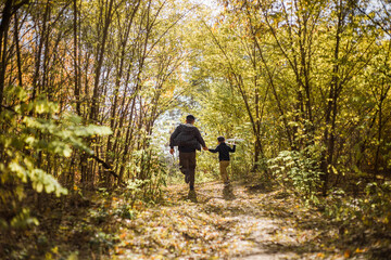 Obraz premium Father and son spend time in forest. Happy dad and child boy enjoying autumn time on vacation in a sunny park. Kids love parents affection and tenderness, lovely family.