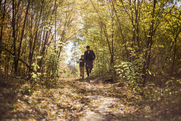 Obraz premium Father and son spend time in forest. Happy dad and child boy enjoying autumn time on vacation in a sunny park. Kids love parents affection and tenderness, lovely family.