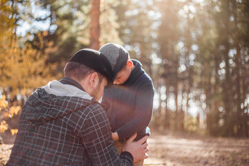 Father`s day. Sad son hugging dad on the  forest background  with copy space. Concept of father-son...