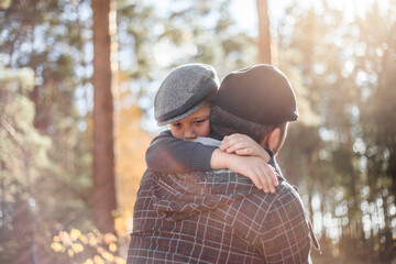 Father`s day. Sad son hugging dad on the  forest background  with copy space. Concept of father-son relationship