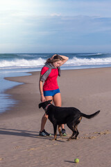 beautiful young woman walking with her dog on the sunny beach
