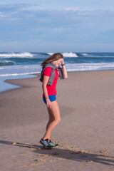 beautiful young woman walking alone on the sunny beach