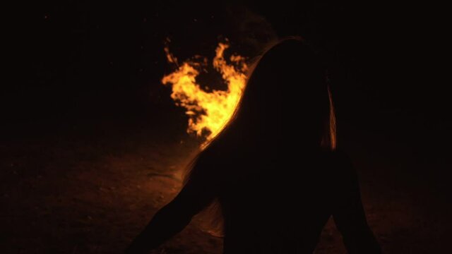 Silhouette of mystic woman in black background of fire fly flame, spark, of contour outline. Adult sexy of young girl witchcraft ceremony ritual dance in underclothes. Outdoor slow motion. Caucasian.