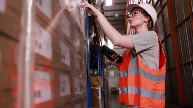 Females warehouse staff or worker using barcode scanner checking shipping stock at depot or distribution center store