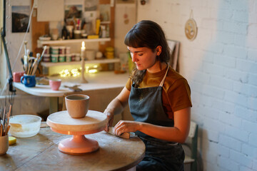 Young woman spend evening in pottery studio busy with handwork relax after stress at work. Calm female shaping and modeling handmade ceramics in workshop. Craftsmanship therapy and relaxation concept