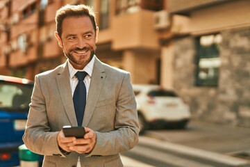 Middle age businessman smiling happy using smartphone at the city.