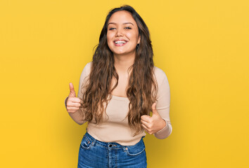 Young hispanic girl wearing casual clothes success sign doing positive gesture with hand, thumbs up smiling and happy. cheerful expression and winner gesture.