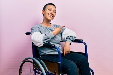 Beautiful hispanic woman with short hair sitting on wheelchair cheerful with a smile of face...