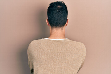 Young hispanic man wearing casual clothes and glasses standing backwards looking away with crossed arms