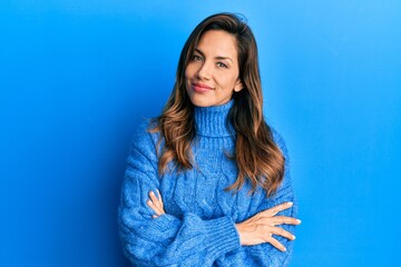 Fototapeta premium Young latin woman wearing casual winter sweater happy face smiling with crossed arms looking at the camera. positive person.