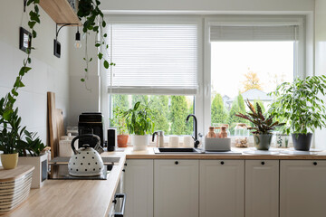 Cozy interior of kitchen with window in scandinavian style. Wooden white furniture i the kitchen...