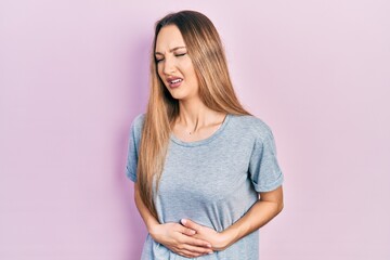 Fototapeta premium Young blonde girl wearing casual t shirt with hand on stomach because nausea, painful disease feeling unwell. ache concept.