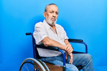 Handsome senior man with beard sitting on wheelchair relaxed with serious expression on face. simple and natural looking at the camera. - Powered by Adobe