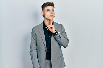 Young caucasian boy with ears dilation wearing business jacket thinking concentrated about doubt...
