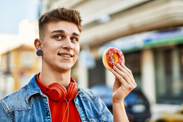 Young caucasian guy smiling holding doughnut at the city