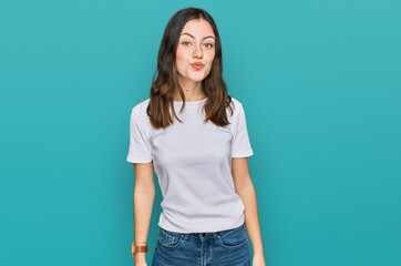 Young beautiful woman wearing casual white t shirt looking at the camera blowing a kiss on air being lovely and sexy. love expression.