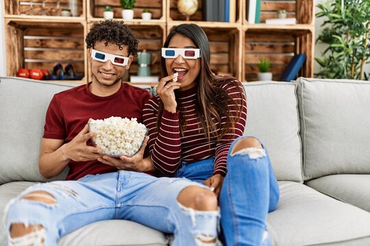Young latin couple smiling happy sitting on the sofa at home.