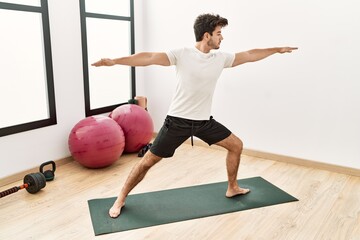 Young hispanic man training yoga exercise at sport center