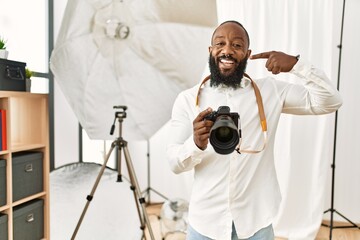 African american photographer man working at photography studio smiling cheerful showing and pointing with fingers teeth and mouth. dental health concept.