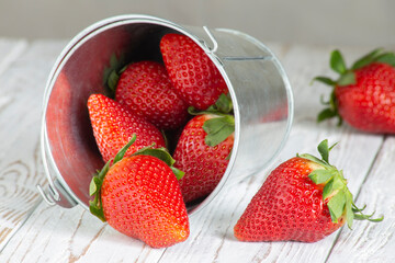 strawberries fruit in a metal container on a white wooden table