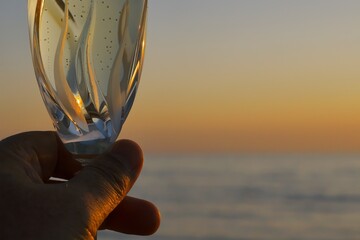 Wine glass with sparkling wine against the backdrop of the sea sunset.