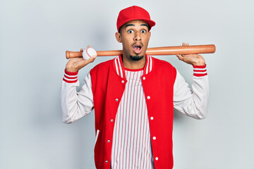 Young african american man playing baseball holding bat and ball afraid and shocked with surprise and amazed expression, fear and excited face.