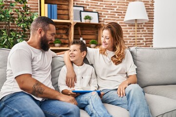 Family using touchpad hugging each other sitting on sofa at home